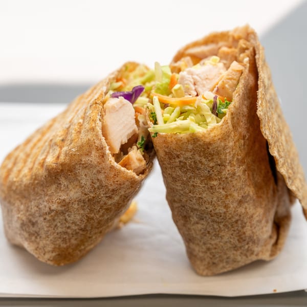 Two halves of a healthy chicken and vegetable wrap, showcasing the fresh ingredients inside.